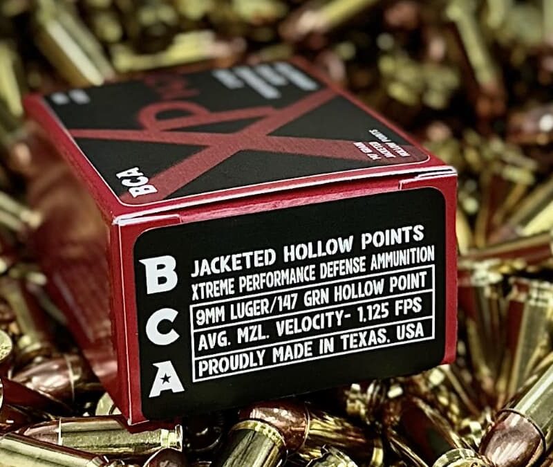 A box of BCA Jacketed Hollow Points on a pile of various types of 9mm ammo for a complete guide for shooters.