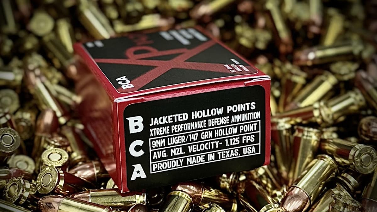 A box of BCA Jacketed Hollow Points on a pile of various types of 9mm ammo for a complete guide for shooters.