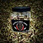 Plastic jar of Buffalo Creek 9mm 124 grain FMJ bullets for range training, surrounded by loose ammunition.