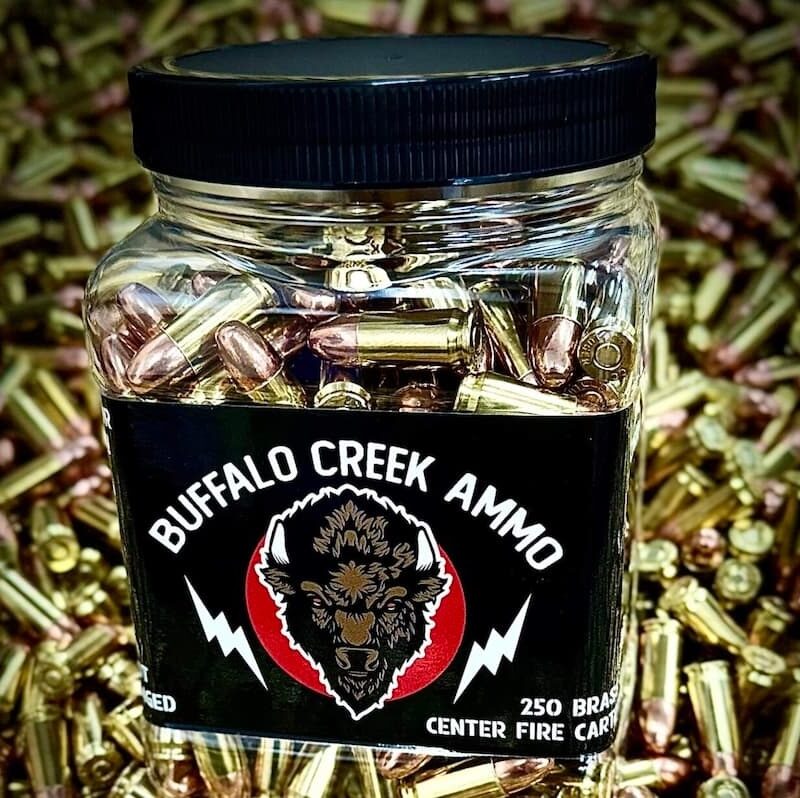A jar of 9mm bulk ammo sitting on top of a pile of loose brass cartridges, illustrating a guide on buying bulk ammo.
